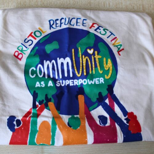 Bristol Refugee Festival 2025 Community as a Superpower T-shirt design, showing colourful people supporting a globe.